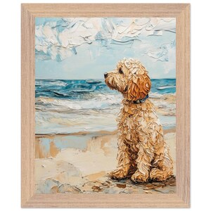 Könnte beinhalten: Gerahmter Kunstdruck eines Golden Doodle Hundes, der an einem Sandstrand sitzt und auf das Meer blickt. Das Gemälde zeigt strukturierte Pinselstriche in Beige-, Blau- und Weißtönen, mit einem hellen Holzrahmen.