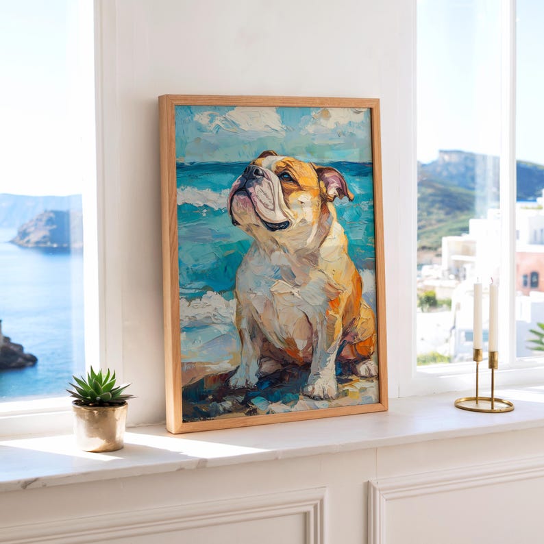 May include: A framed art print of a bulldog sitting on a beach, with a blue ocean and sky background. The artwork features a light brown wooden frame and a colorful, textured painting style. The dog is depicted with a light brown and white coat.