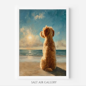 May include: A framed art print showing a golden doodle dog on a sandy beach, looking out at the sea under a bright, sunny sky. The artwork has a painterly style with soft brushstrokes and a warm colour palette.