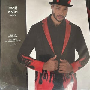Puede incluir: Una chaqueta negra con solapas rojas brillantes y patrones de llamas rojas en el dobladillo inferior y los puños. La chaqueta se lleva con una camisa negra y un sombrero fedora negro con dos cuernos de diablo rojos. Texto JACKET VESTON CHAQUETA.
