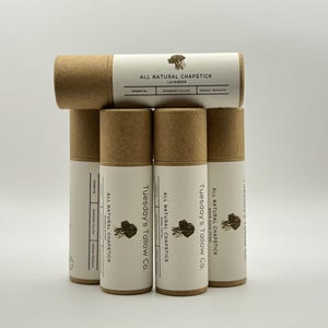 May include: A collection of natural chapsticks in cardboard tubes. The labels read "All Natural Chapstick" with different scents: Lavender, White Eucalyptus, and Rose Petal. The brand name "Tuesday's Tallow Co." is also visible.