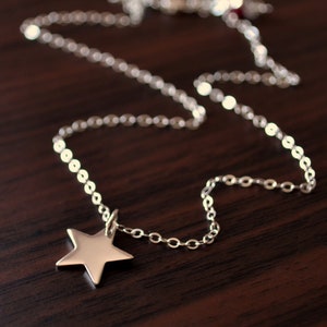 May include: A silver chain necklace with a star pendant. The chain is made of small, linked circles. The star is a simple, five-pointed design.