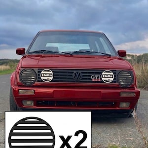 Puede incluir: Un juego de dos rejillas circulares negras para faros con lamas horizontales. Estas cubiertas protectoras están diseñadas para luces de automóvil redondas y se muestran como un par, con un gráfico que indica una cantidad de dos unidades.