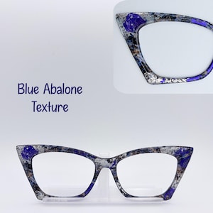 May include: Cat-eye glasses frames featuring a blue abalone texture with silver and dark blue mottled patterns. The frames are displayed in full and as a partial detail view. The text Blue Abalone Texture is printed on the left side.