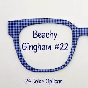 May include: Eyeglass frames featuring a blue and white gingham check pattern. The text Beachy Gingham #22 is printed in the center of the lens area in dark blue. Below the frame, the text 24 Color Options is printed in dark blue.