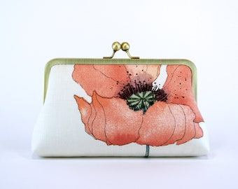 May include: A white clutch purse with a brass clasp and a large pink poppy flower design.