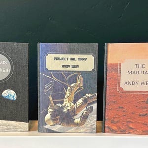 May include: A set of three ceramic mugs with a speckled, matte finish. Each mug features a different color: light blue, cream, and gray. The mugs have a simple, modern design and a comfortable handle.