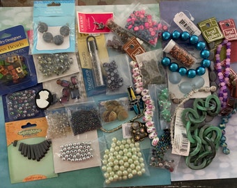 May include: A collection of various beads and jewelry-making supplies. The image includes glass beads, gemstone pendants, pearl beads, and other decorative elements in various colors and shapes. Some items are packaged in clear plastic bags.