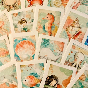 May include: A collection of watercolor art cards featuring marine life and mermaids. The cards showcase illustrations of a crab, seahorse, whale, octopus, fish, and mermaid. The color palette includes shades of blue, coral, and teal, creating a whimsical underwater theme.