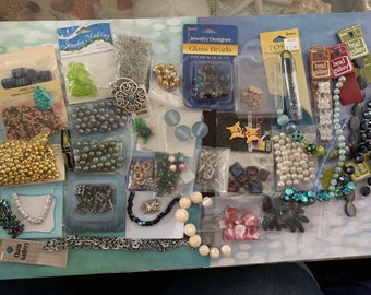 May include: A collection of jewelry-making supplies, including various beads in gold, silver, and pearl colors, along with clasps, chains, and other accessories. Packaged in clear plastic bags and labeled with "Jewelry Making" and "Bead Gallery" tags.