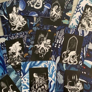 May include: A collection of tarot cards featuring black and white illustrations of octopuses and other sea creatures. The cards are set against a backdrop of blue and white patterned paper with marine life motifs.