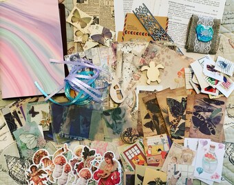 May include: A collection of vintage ephemera, including patterned papers, butterfly stamps, stickers, and a notebook with a pastel swirl cover. Decorative elements include wooden cutouts, ribbons, and lace. The items are arranged on a quilted surface.