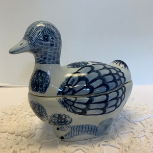 May include: A blue and white ceramic duck shaped trinket box. The duck has a detailed design with blue and white patterns.