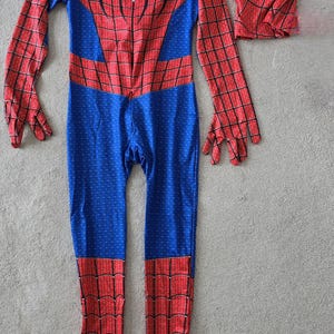 Puede incluir: Un disfraz de Spider-Man rojo y azul con una m&aacute;scara a juego. El traje de cuerpo entero presenta un patr&oacute;n de telara&ntilde;a en las secciones rojas y un emblema de ara&ntilde;a en el pecho. La m&aacute;scara tiene ojos blancos.