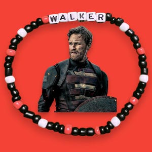 May include: A beaded bracelet with the name "WALKER" spelled out in white letter beads. The bracelet features black, red, and white beads. The background is red, and there is an image of a man in a black and red outfit.
