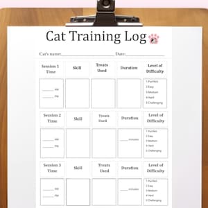 Può includere: Un foglio bianco "Cat Training Log" su un appoggio di legno. Il registro include sezioni per tempo, abilità, dolcetti usati, durata e livello di difficoltà. Il testo è nero, con una grafica di impronta di zampa rosa.