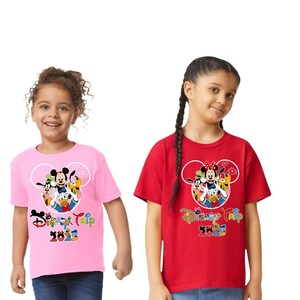 May include: Two children wearing pink and red t-shirts with a Disney Trip 2023 graphic. The graphic features Mickey Mouse, Minnie Mouse, Donald Duck, Goofy, and Pluto inside a Mickey Mouse head outline.
