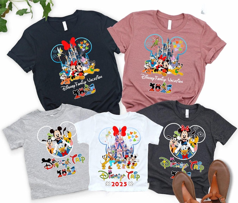 May include: Collection of short-sleeved t-shirts with Disney characters. Designs feature Mickey and Minnie Mouse, Donald Duck, and Goofy, with text reading "Disney Family Vacation 2023" and "Disney Trip 2023". Colours include black, pink, grey, and white.