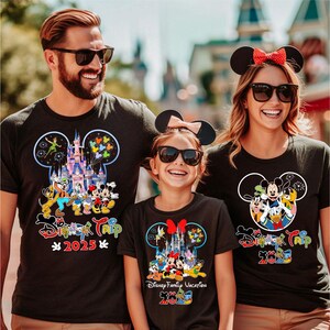 May include: Black t-shirts with Disney character designs. Each shirt features a Mickey Mouse head outline with a castle, characters, and the text "Disney Trip 2025". The family is wearing matching shirts.