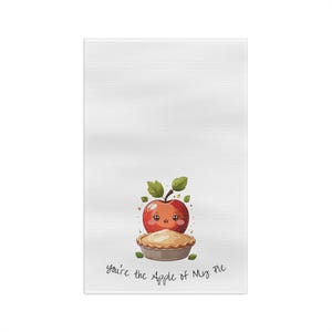May include: White kitchen towel with a cartoon apple and pie design. The red apple has a smiling face and green leaves. The pie is in a metal tin. Text reads "you're the Apple of My Pie."
