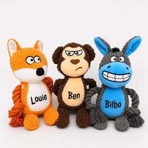 May include: Three plush animal toys with rope limbs. An orange fox labelled Louie, a brown monkey labelled Ben, and a blue and grey donkey labelled Bilbo. Each toy features a textured fabric body, embroidered facial expressions, and knotted rope arms.