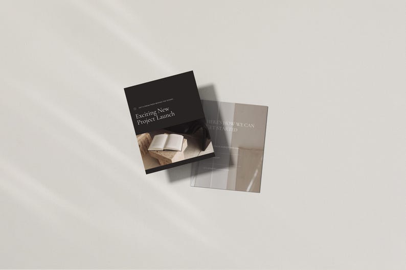 May include: Two brochures with text. The top brochure is black with the text "Exciting New Project Launch". The bottom brochure is light beige with the text "Here's How We Can Get Started". The brochures are on a white surface.