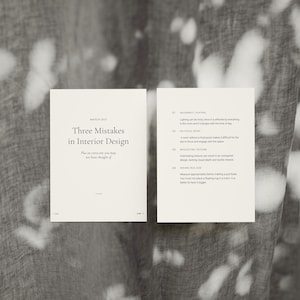 May include: Two open, off-white pages of a booklet titled "Three Mistakes in Interior Design" with text on a gray background. The left page has the title and the right page lists four mistakes. The background has a pattern of white shapes.