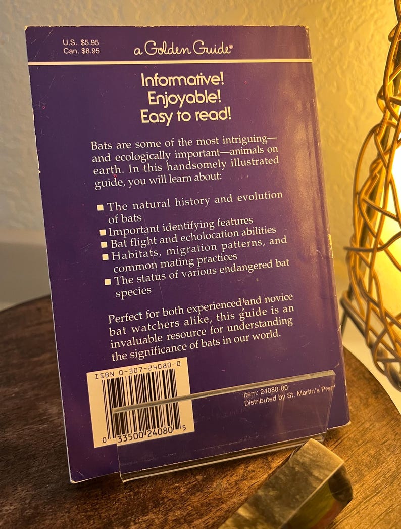 May include: A purple Golden Guide book about bats, featuring text that reads "Informative! Enjoyable! Easy to read!" The book's cover includes information on bat species, habitats, and evolution. The price is $5.95.