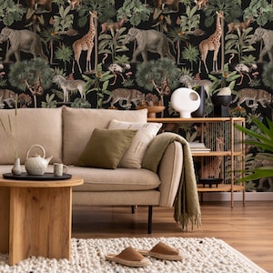 Könnte beinhalten: Ein Wohnzimmer mit beigem Sofa, oliv- und cremefarbenen Kissen und einem Holztisch. Die Tapete zeigt eine Dschungelszene mit Giraffen, Elefanten und Zebras. Ein Teppich und dekorative Elemente ergänzen das Gesamtbild.