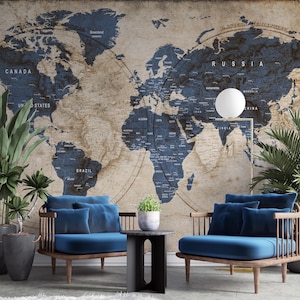 May include: A room featuring two blue cushioned armchairs with wooden frames, a small black side table, and potted plants. The background is a large world map in shades of blue and brown, with the names of countries visible.