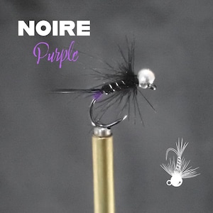 May include: A close-up of a fishing fly with the text "NOIRE Purple". The fly has a black body, a silver hook, and a white bead head. The fly is mounted on a gold-colored stand. A white illustration of a fly is in the bottom right corner.