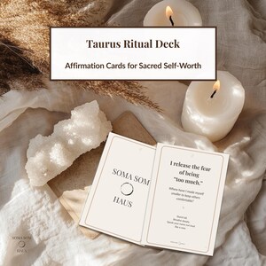 Könnte beinhalten: Ein Taurus Ritual Deck mit Affirmationskarten für heiligen Selbstwert. Die Karten sind geöffnet und zeigen Text auf cremefarbenem Hintergrund. Das Deck befindet sich neben einem weißen Kristall und zwei brennenden Kerzen. Der Text auf den Karten lautet "Soma Som Haus" und "Ich lasse die Angst los, zu viel zu sein."