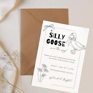 May include: A baby shower invitation with the text "A SILLY GOOSE is on the way!" in black font. The invitation features a line drawing of a goose and floral accents. An envelope is behind the invitation.