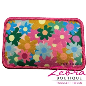 May include: Rectangular patch with a vibrant floral pattern in pink, blue, green, and yellow. The patch has a pink stitched border and the text "THE FUNKY" is visible. The bottom right corner has the text "Zebra BOUTIQUE TODDLER • TWEEN".