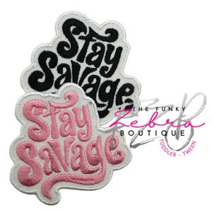 May include: Two embroidered patches with the words "Stay Savage" in a cursive font. One patch is black with white trim, and the other is pink with white trim. The patches are on a white background.