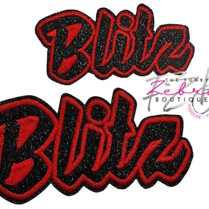 May include: Two embroidered patches with the word "Blitz" in a bold, stylized font. The letters are red with a black glittery outline. The patches are likely for clothing or accessories.