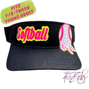 May include: Black visor with the word "Softball" in bright pink with a yellow outline. A softball graphic with pink stitching and colorful sprinkles is on the right. The visor fits 7/8-Tween Young Adult.