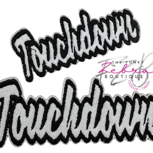 May include: Two embroidered patches with the word "Touchdown" in a black and white design. The patches have a textured, glittery appearance. The Funky Zeberta Boutique logo is visible in the background.