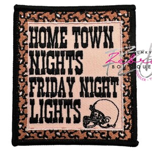 May include: Square patch with the words "HOME TOWN NIGHTS FRIDAY NIGHT LIGHTS" in black block letters. A football helmet graphic is at the bottom. The patch has a leopard print border and a black stitched edge.