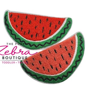 May include: Two embroidered watermelon slice patches. The patches feature a red interior with black seeds, a green rind, and a white border. The text "THE FUNK Zebra BOUTIQUE TODDLER" is in the lower left corner.