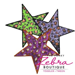 May include: Three sequined star-shaped patches in green, purple, and violet with leopard print patterns. The stars have black borders and are arranged on a white background. The text "The Funky Zebra Boutique" is visible.