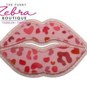 May include: A pink lip-shaped patch with a glittery border and a pattern of red, pink, and orange spots. The text "THE FUNKY Zebra BOUTIQUE TODDLER • TWEEN" is in the upper left corner.