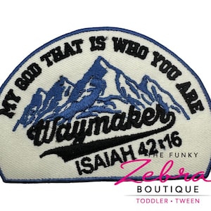 May include: Embroidered patch with the text "MY GOD THAT IS WHO YOU ARE" in black, arched around the top. The patch features a blue mountain design and the word "Waymaker" in black script. The text "ISAIAH 42:16" is also included.