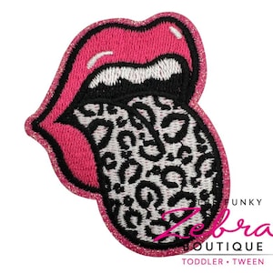 May include: Embroidered patch featuring a pair of pink lips with a black and white leopard print tongue. The patch has a glittery pink border and the text "The Funky Zebra Boutique, Toddler, Tween".