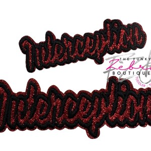 May include: Two embroidered patches with the word "Interception" in a cursive font. The patches have a red glitter base with black outlining. The Funky Zeberta Boutique logo is in the background.