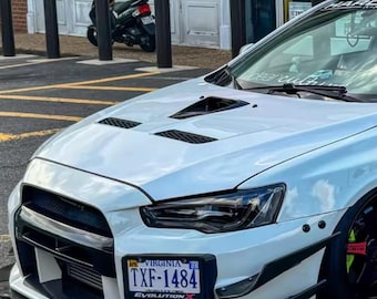 Könnte beinhalten: Eine weiße Mitsubishi Lancer Evolution X Limousine mit belüfteter Motorhaube, schwarzen Frontstoßstangenakzenten und einem Virginia-Nummernschild mit der Aufschrift TXF-1484. Der Text SPEEDMEMORY und EVERY GREAT ACHIEVEMENT BEGINS WITH A DREAM ist eingeblendet.