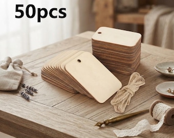 May include: A set of 50 rectangular light-coloured wooden tags with rounded corners and a single pre-drilled hole at the top. The tags are arranged in two stacks, one lying flat and one standing upright, accompanied by a bundle of natural jute twine.
