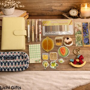 May include: A collection of stationery and decorative items on a wooden surface. Includes a yellow planner, pens, stickers, a pencil case, and a rocking horse keychain. The items are arranged with a warm, inviting aesthetic.