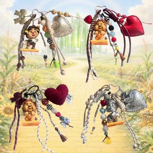 May include: Four decorative bag charms featuring miniature figures of characters from The Wizard of Oz. Each charm includes a metallic or textured heart, assorted beads, tassels, and cords in various colors, attached to a metal ring clasp.
