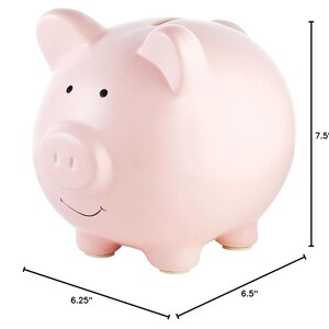May include: A pink ceramic piggy bank with a smiling face and a small snout. It measures 7.5 inches tall, 6.25 inches wide, and 6.5 inches long.